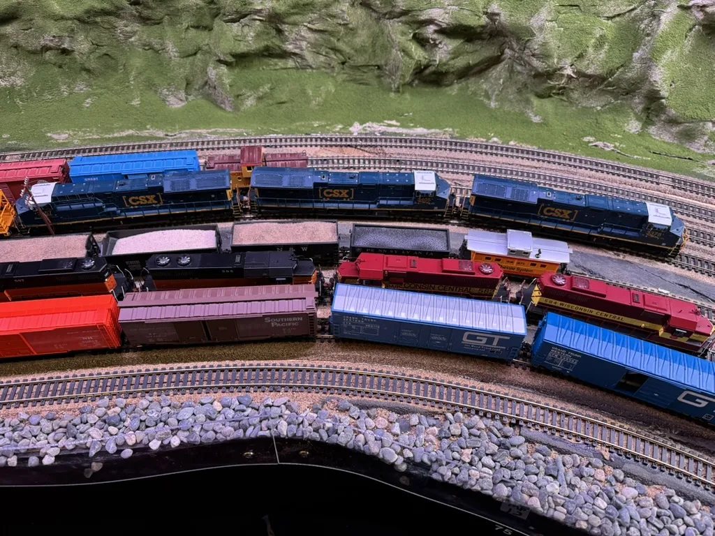 A collection of model locomotives and freight cars arranged across a staging yard